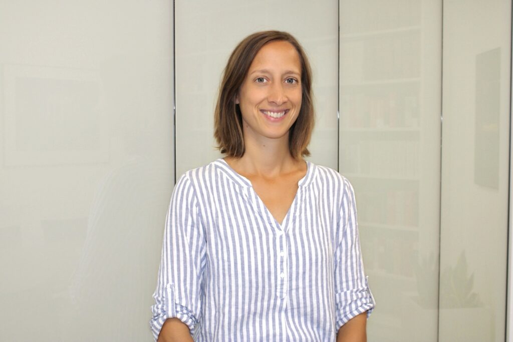 Rechtsanwaltsfachangestellte Jennifer Zeller in heller Kanzleiumgebung mit gestreifter Bluse.